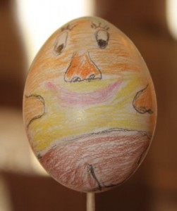 Ei Nummer 5 zeigt ein aus Kreide gemaltes Oster-Gesicht in vielen bunten Farben.